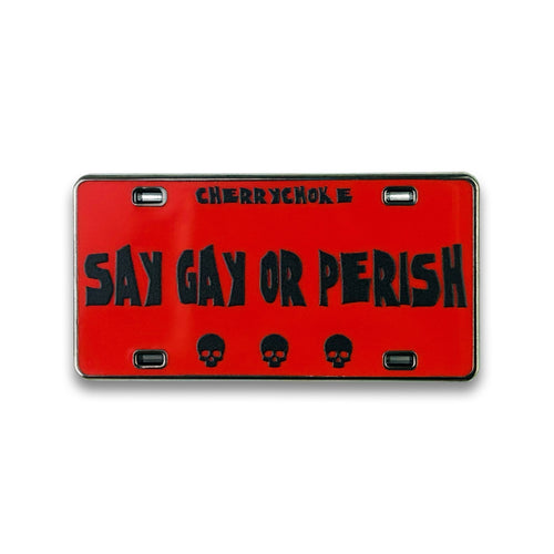 A red novelty license plate with black text reading 'SAY GAY OR PERISH' and 'CHERRYCHOKE' at the top, plus three black skulls along the bottom, shown on a white background.